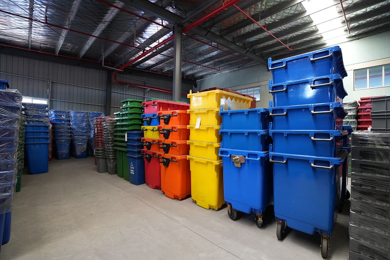 plastic garbage bins organized in warehouse